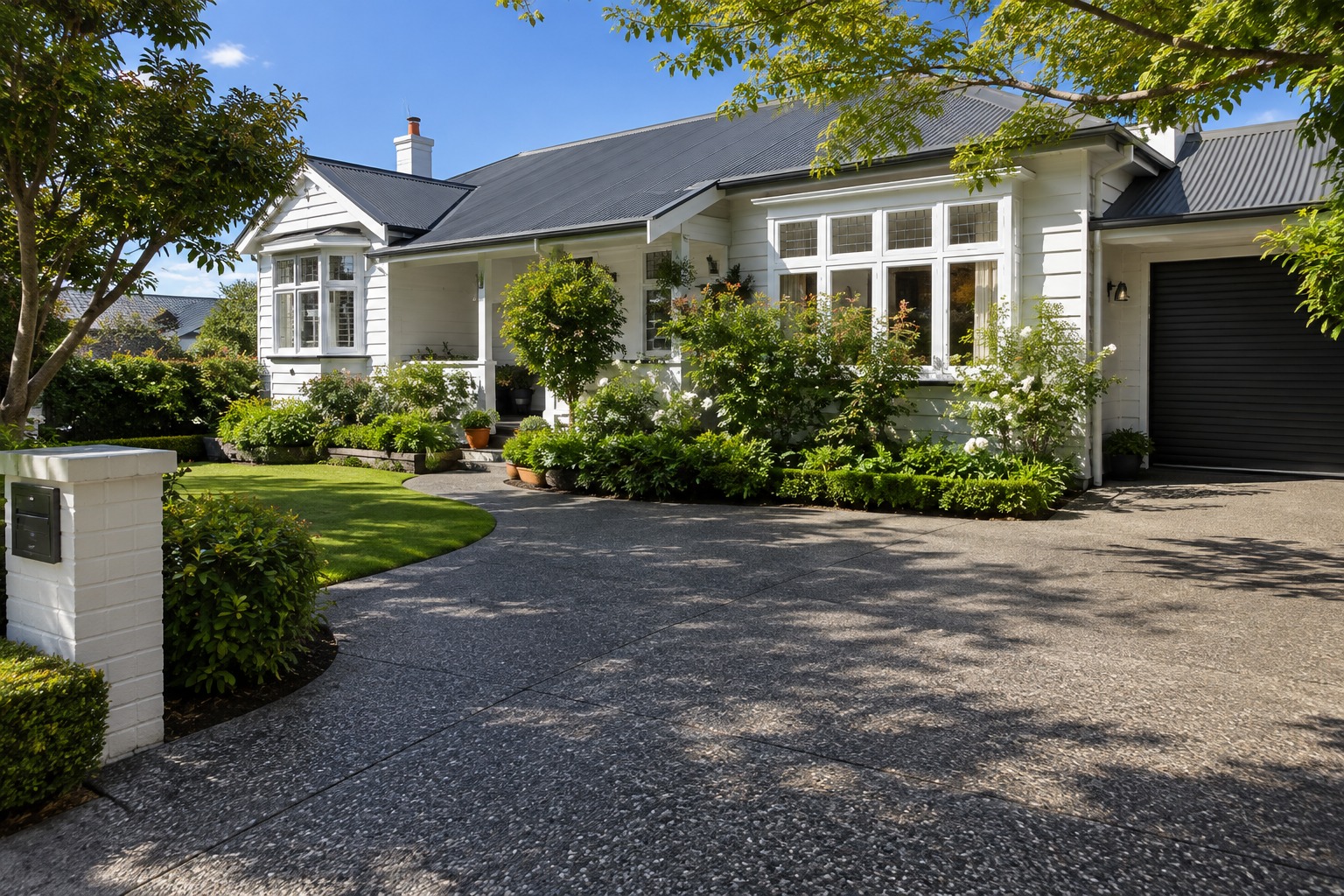 Pebble aggregate drive outside a white timber-clad house, Cairns
