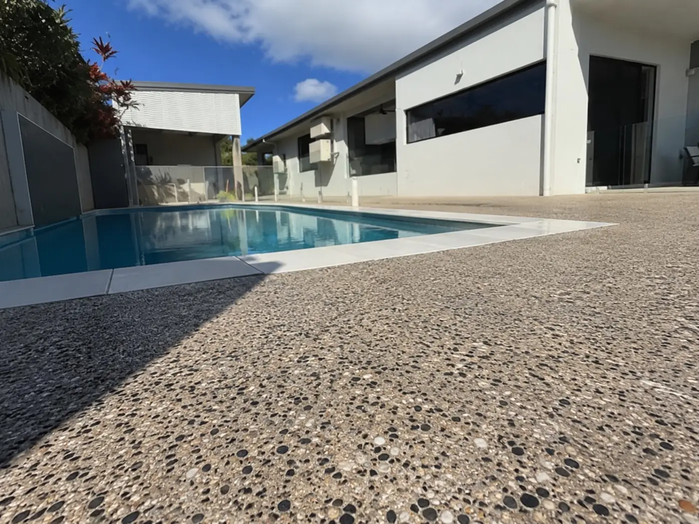 Exposed aggregate pool surround beside a lap pool and modern home, Cairns